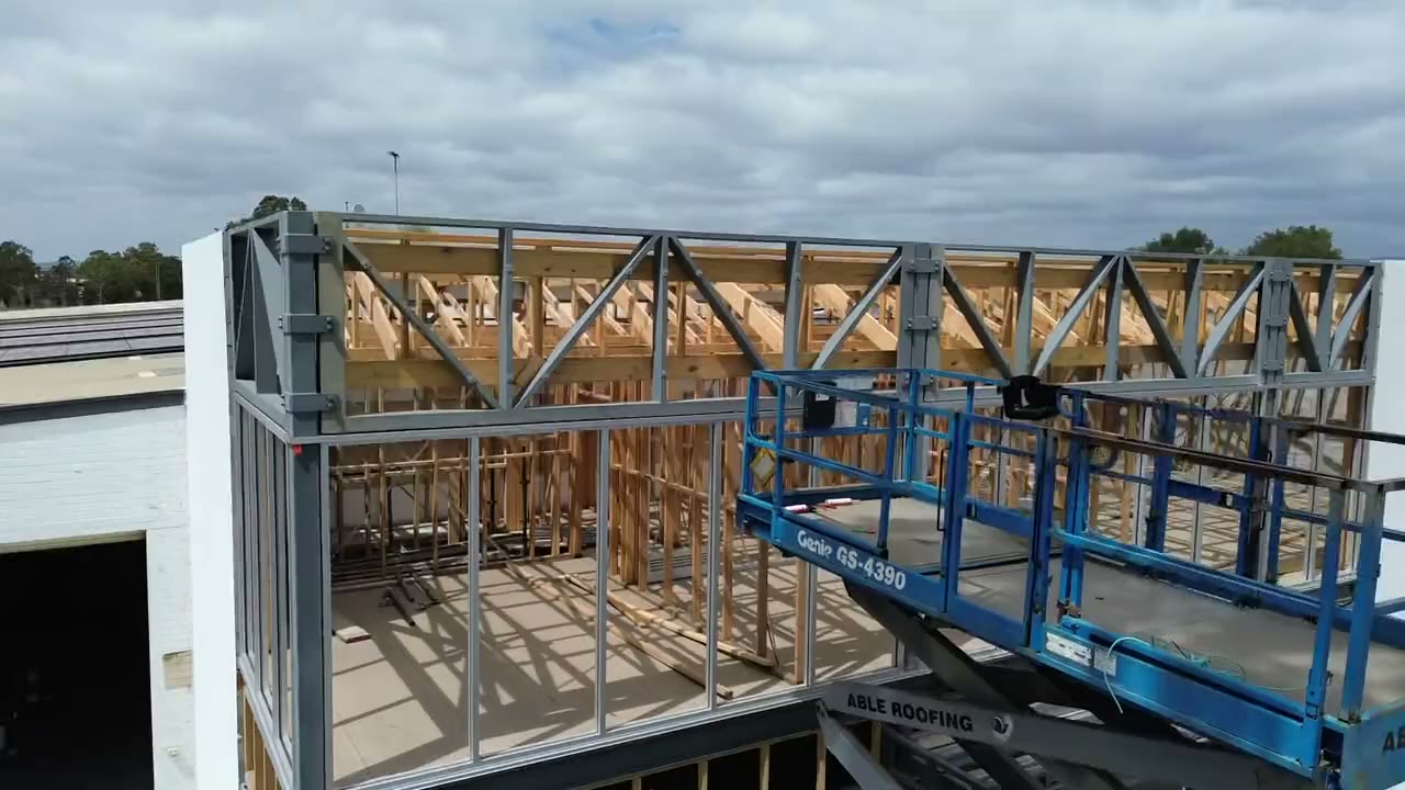 Drone view of timber and steel roof trusses on a Russo Built commercial job, rising into full view